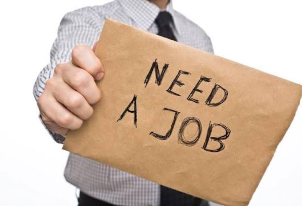 Man holding a handwritten Need A Job sign, representing overseas jobseekers